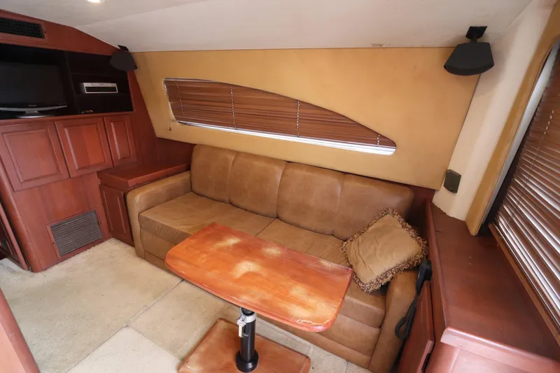 Slide: The Image of 2004 Luhrs 38 Convertible interior with beige sofa, wooden table, and entertainment unit. - 2