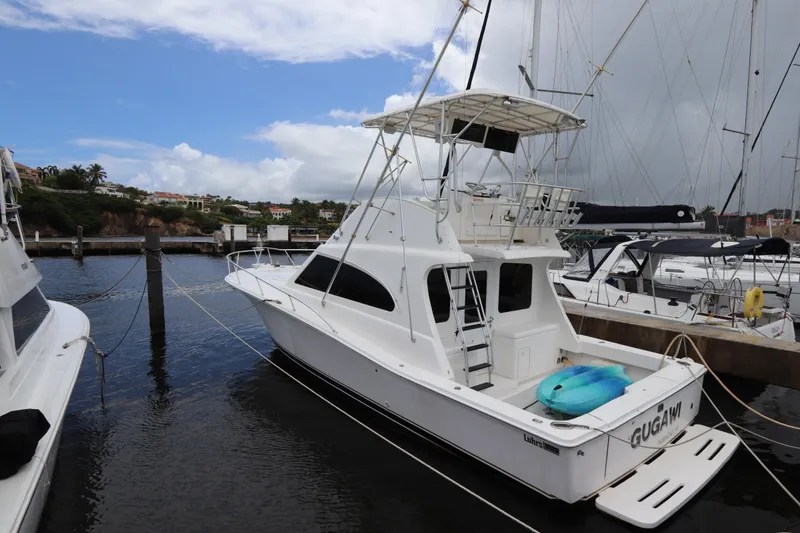 Slide: The Image of 2004 Luhrs 38 Convertible yacht docked at marina, featuring spacious deck and flybridge. - 21