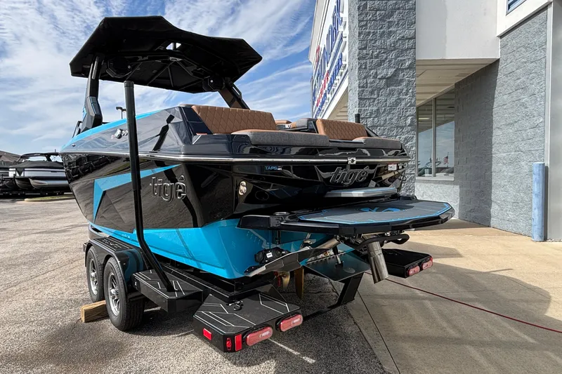 Slide: The Image of 2026 Tigé Z3 boat on trailer, blue and black design, parked outside dealership. - 2