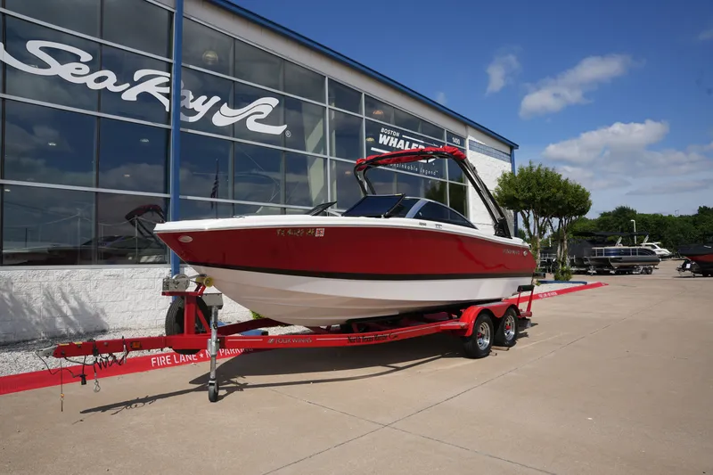 Slide: The Image of Red 2019 Four Winns H230 boat on trailer outside a showroom. - 1