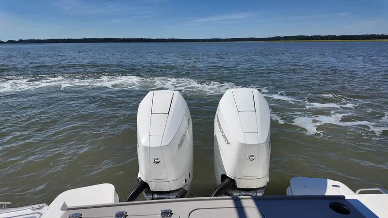 Slide: The Image of Two outboard engines on a boat in calm water with a wooded shoreline in the background. - 4