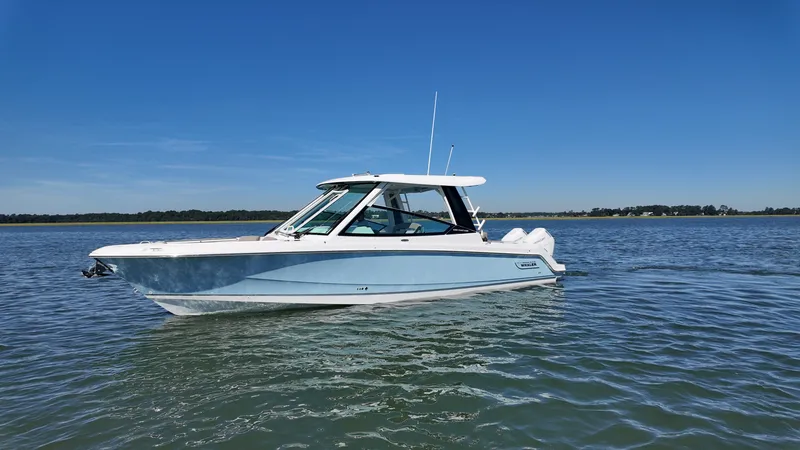 Slide: The Image of Boston Whaler 330 Vantage 2027 on calm water, with a clear blue sky in the background. - 1