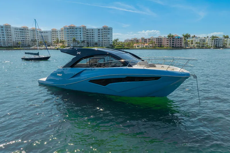 Slide: The Image of 2025 NX Boats NX41 HORIZON yacht on calm water near luxury waterfront buildings. - 10