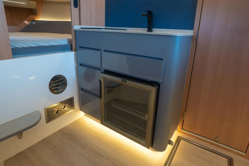 Slide: The Image of Interior of 2025 NX Boats NX41 HORIZON, featuring modern kitchenette with fridge and ambient lighting. - 44