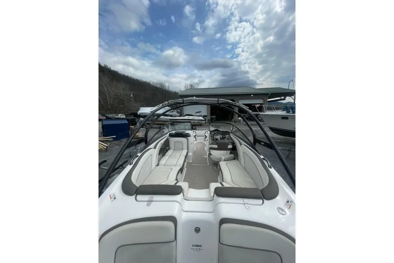 Slide: The Image of 2014 Yamaha Boats 242 Limited interior with seating and helm, under cloudy sky. - 5