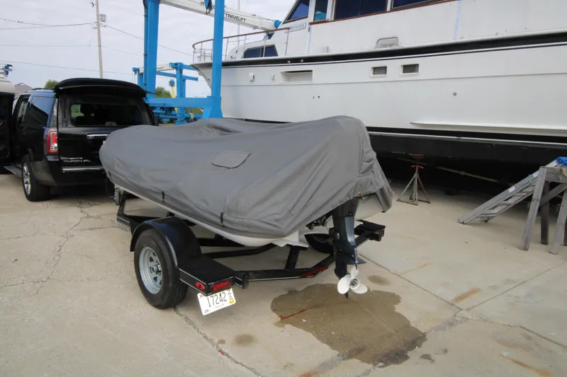 Slide: The Image of Covered 2018 Avon Seasport 400 Deluxe NEO boat on trailer, parked near a yacht. - 13
