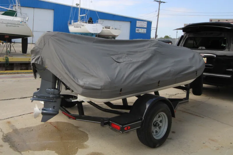 Slide: The Image of 2018 Avon Seasport 400 Deluxe NEO boat covered on trailer, parked near marina. - 16