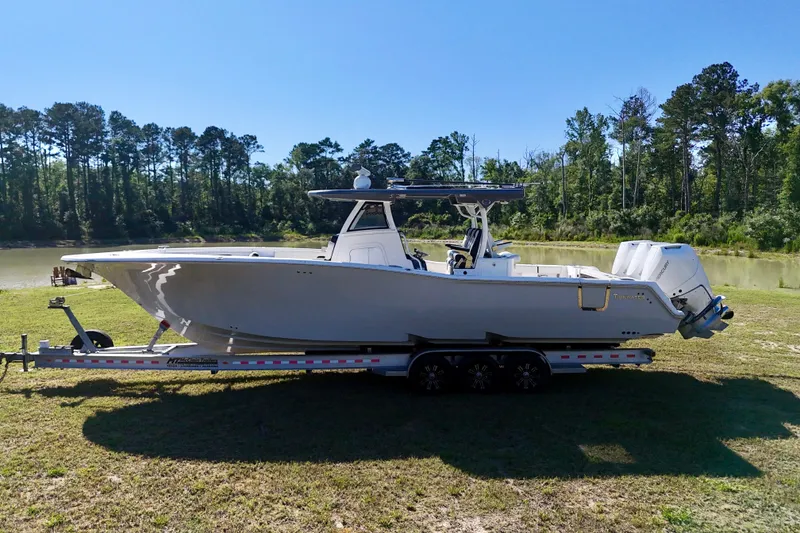 Slide: The Image of 2024 Tidewater 380 CC Adventure boat on trailer, parked near a scenic lake. - 11