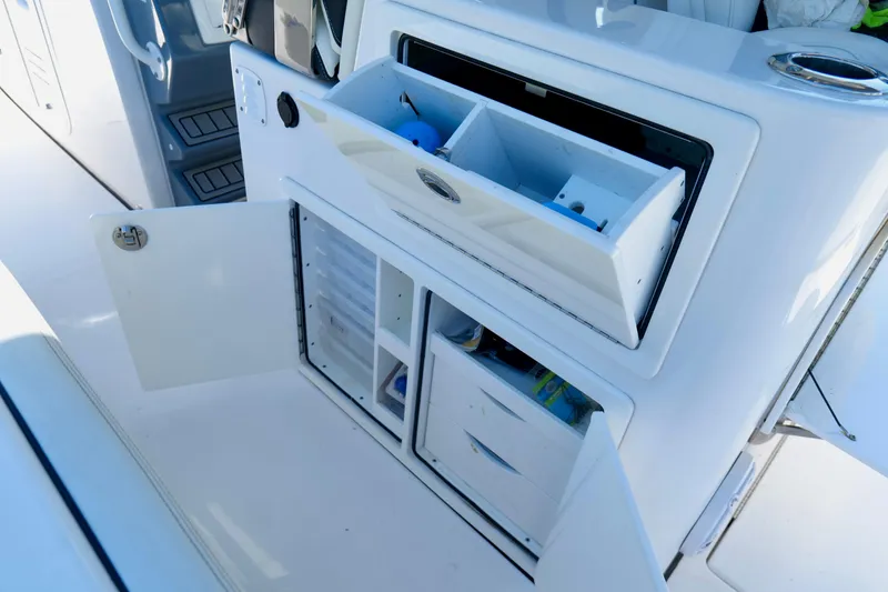 Slide: The Image of 2024 Tidewater 380 CC Adventure boat storage compartments with open doors and organized interior. - 26