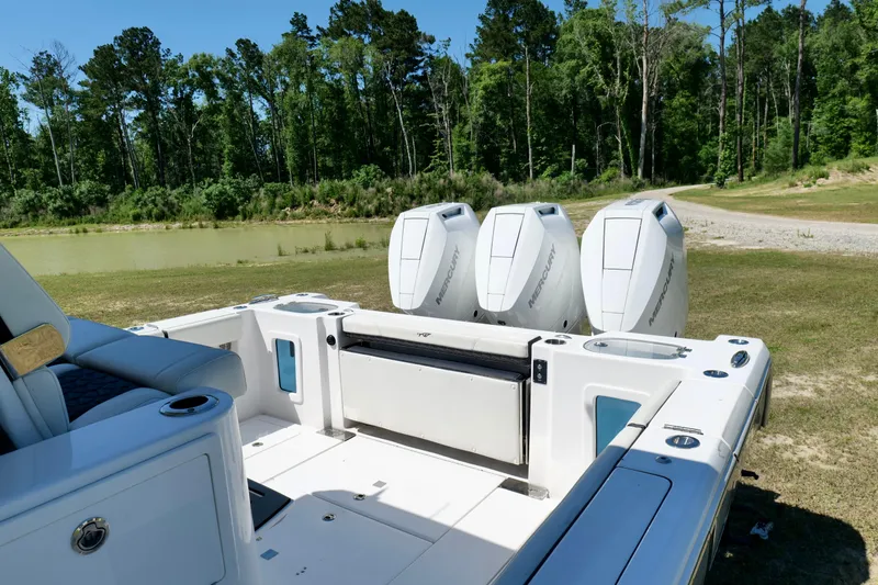 Slide: The Image of 2024 Tidewater 380 CC Adventure boat with triple Mercury engines, parked near a serene lake. - 29
