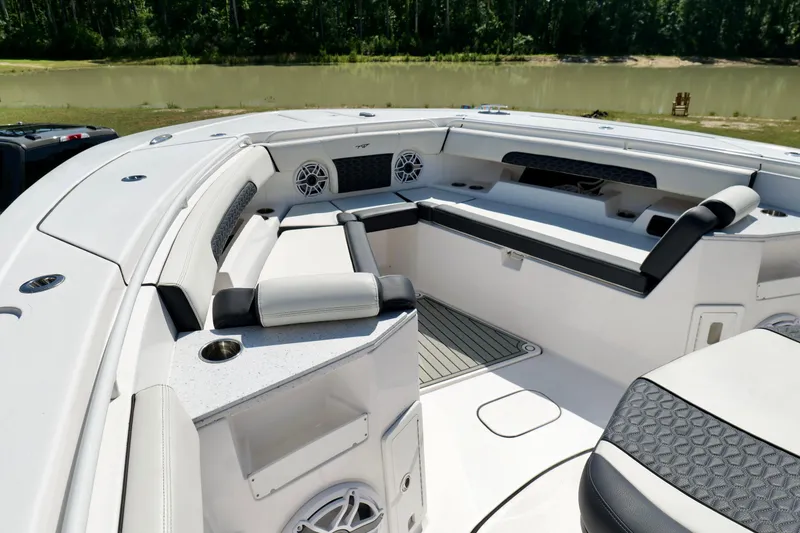 Slide: The Image of 2024 Tidewater 380 CC Adventure boat interior with seating and speakers, near a serene lake. - 32