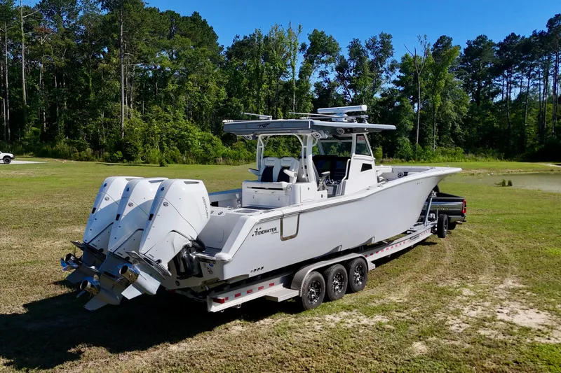 Slide: The Image of 2024 Tidewater 380 CC Adventure boat on trailer, surrounded by lush greenery. - 6