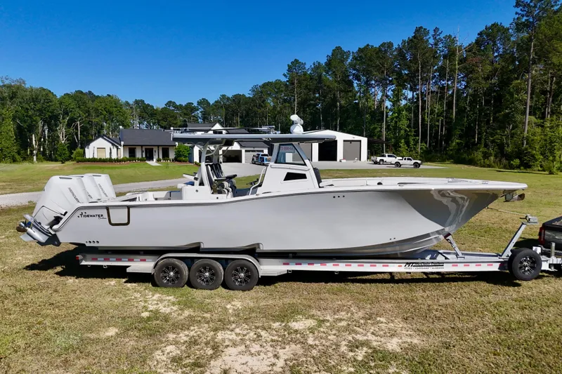 Slide: The Image of 2024 Tidewater 380 CC Adventure boat on trailer, parked in a grassy area. - 7