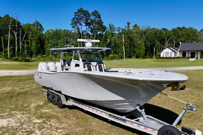 Slide: The Image of 2024 Tidewater 380 CC Adventure boat on trailer, set against a lush green landscape. - 8