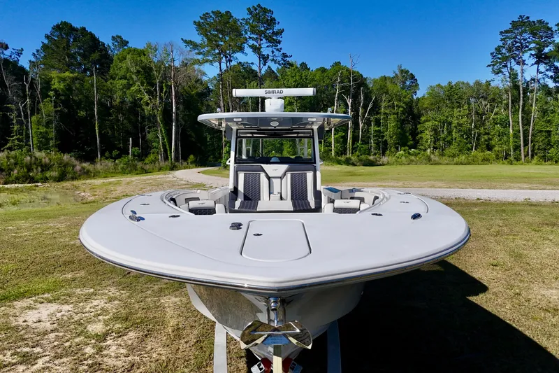 Slide: The Image of 2024 Tidewater 380 CC Adventure boat on grassy terrain, surrounded by trees. - 9