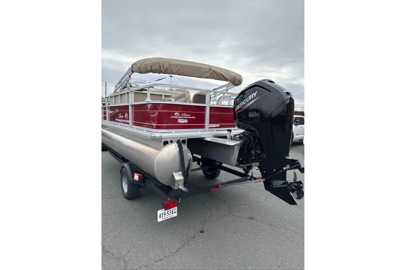 Slide: The Image of 2024 Sun Tracker Bass Buggy 18 DLX pontoon boat with Mercury outboard motor on trailer. - 2