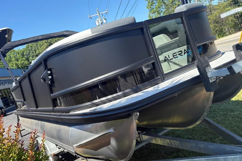 The Image of 2026 Alera 23Q pontoon boat on trailer, sleek black design, sunny day. - 0