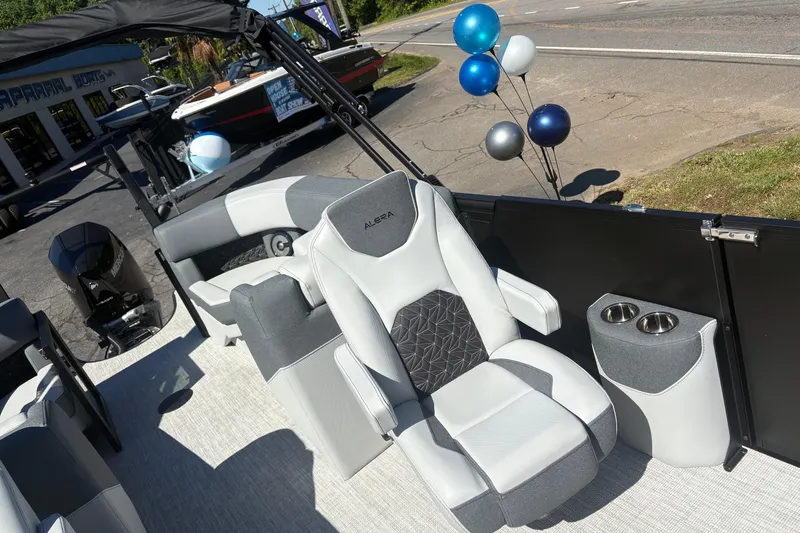 Slide: The Image of 2026 Alera 23Q boat interior with plush seating and cup holders, displayed outdoors with balloons. - 8