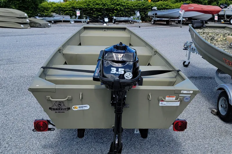 Slide: The Image of 2025 Tracker Grizzly 10 Jon boat with 3.5 HP motor, parked on gravel. - 3