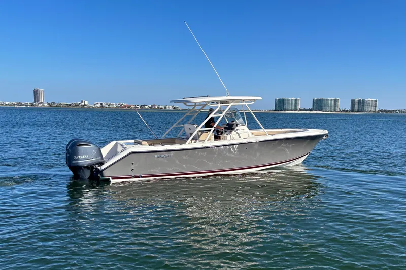 The Image of 2015 Pursuit S 280 Sport boat cruising on calm water with city skyline backdrop. - 0