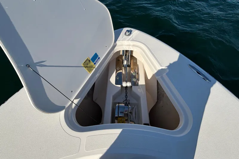 Slide: The Image of Open anchor compartment on 2015 Pursuit S 280 Sport boat, showing anchor chain and mechanism. - 14