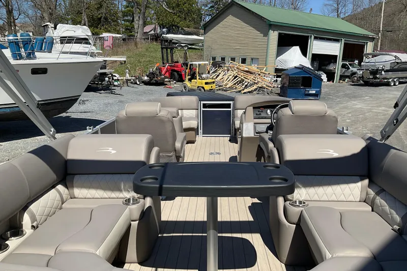 Slide: The Image of 2019 Bennington SX 20 SSRX pontoon boat with spacious seating and table, docked outdoors. - 21