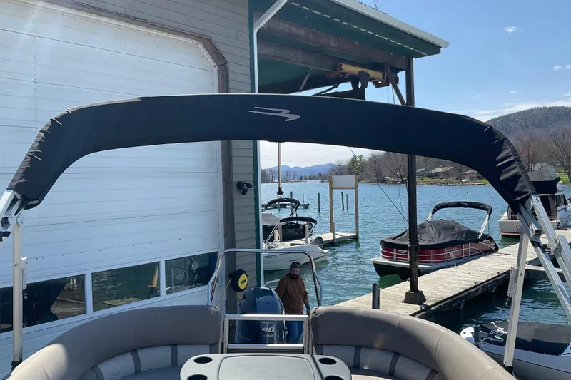 Slide: The Image of 2019 Bennington SX 20 SSRX pontoon boat docked at a scenic lakeside marina. - 23