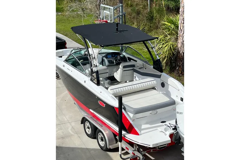 Slide: The Image of 2019 Cobalt 25SC boat with black canopy and sleek design on a trailer. - 2