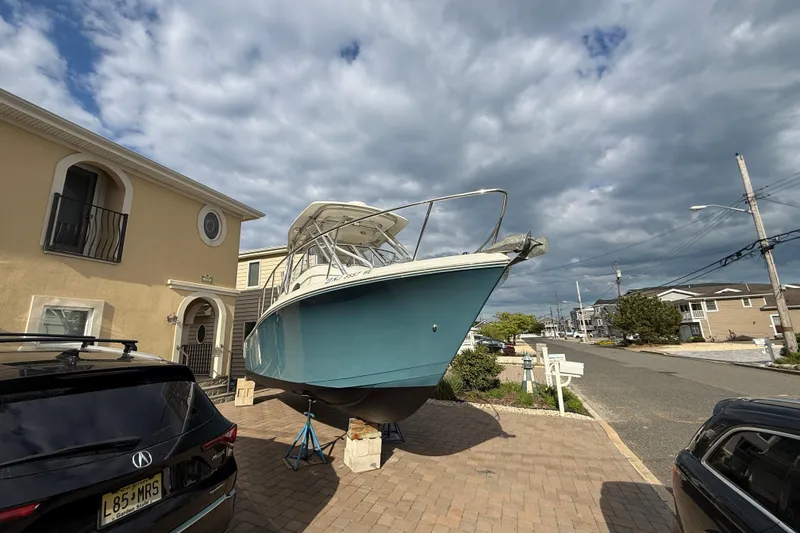 Slide: The Image of 2012 Sailfish 2680 WAC boat on driveway, under cloudy sky, near residential area. - 1