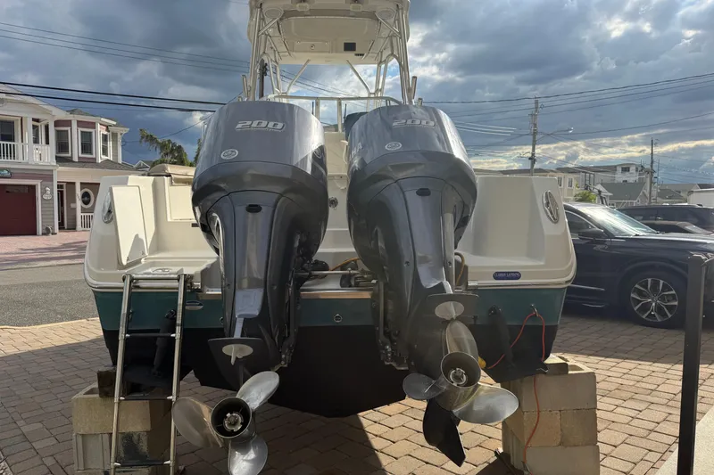 Slide: The Image of 2012 Sailfish 2680 WAC boat with twin 200 horsepower engines, parked on a driveway. - 10