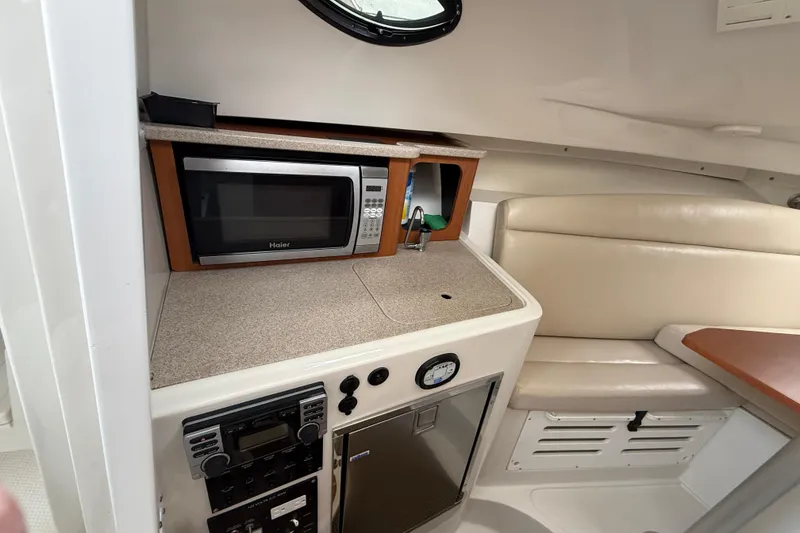 Slide: The Image of 2012 Sailfish 2680 WAC cabin interior with microwave, seating, and control panel. - 26
