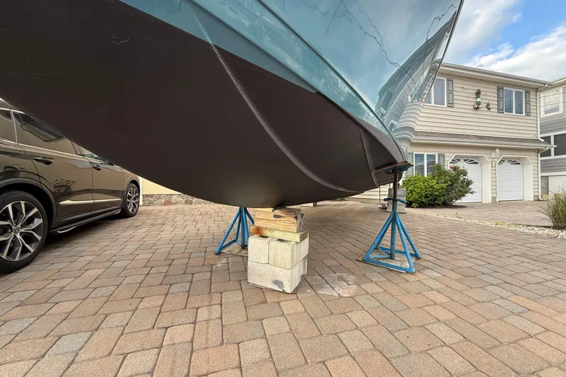 Slide: The Image of 2012 Sailfish 2680 WAC boat on stands in driveway, near a house and car. - 33