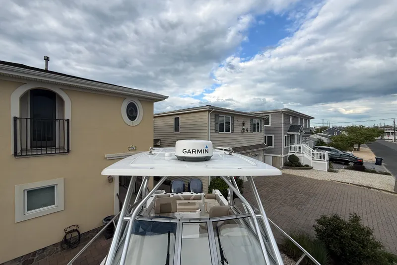 Slide: The Image of 2012 Sailfish 2680 WAC boat with Garmin radar, parked near residential houses under cloudy sky. - 6