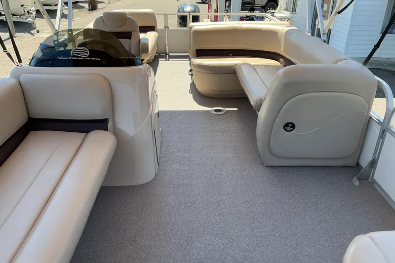 Slide: The Image of 2017 Sun Tracker Party Barge 24 DLX interior with beige seating and helm. - 14