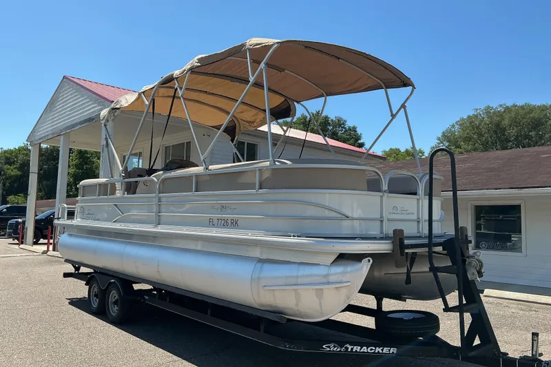 Slide: The Image of 2017 Sun Tracker Party Barge 24 DLX pontoon boat on trailer, parked near a building. - 3