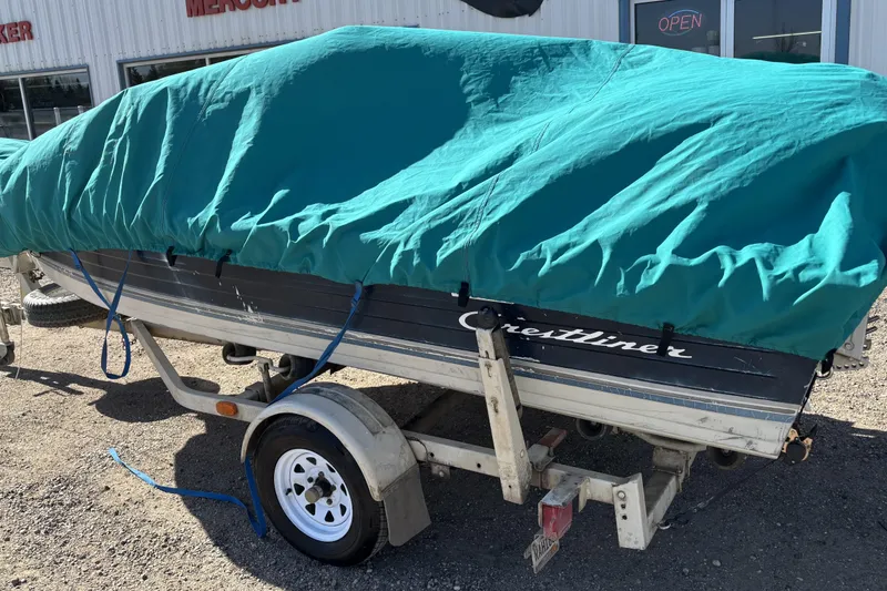 Slide: The Image of 1983 Crestliner 16 boat covered with a teal tarp on a trailer. - 12