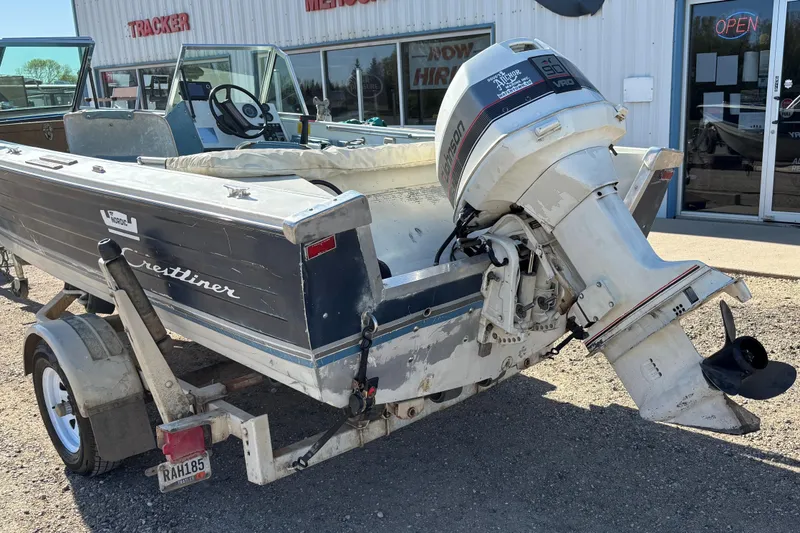 Slide: The Image of 1983 Crestliner 16 boat with Johnson outboard motor on trailer, parked outside dealership. - 3