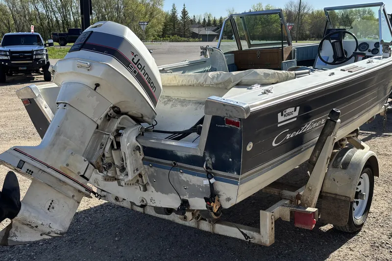 Slide: The Image of 1983 Crestliner 16 boat with Johnson 90 outboard motor on trailer, parked outdoors. - 5