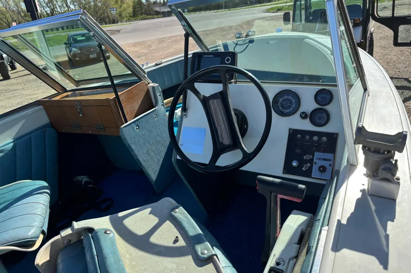 Slide: The Image of 1983 Crestliner 16 boat interior with steering wheel, dashboard, and blue seating. - 9