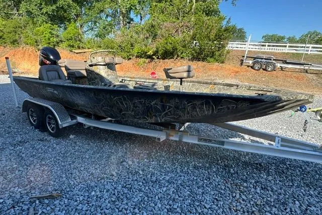Slide: The Image of 2026 War Eagle 2170 Blackhawk boat on trailer, parked on gravel, surrounded by trees. - 4