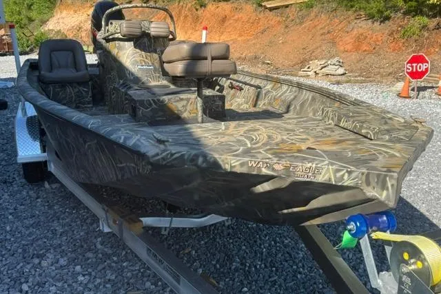 Slide: The Image of 2026 War Eagle 2170 Blackhawk boat on trailer, camo design, parked on gravel. - 5