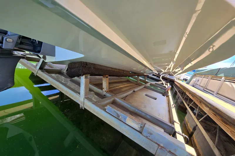 Slide: The Image of Underneath view of a 2016 Cobalt R3 boat on a metal lift over green water. - 42