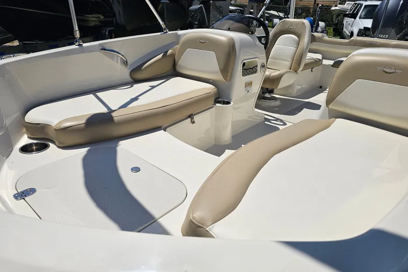 Slide: The Image of 2019 Stingray 182 SC boat interior with beige and white seating, steering console, and cup holders. - 12