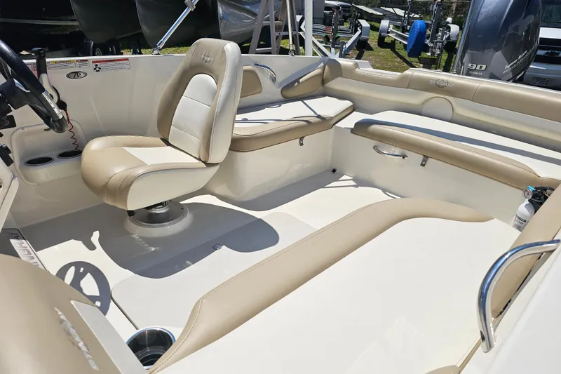 Slide: The Image of 2019 Stingray 182 SC boat interior with beige and white seating, steering wheel, and cup holders. - 14