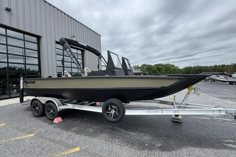 The Image of 2026 SeaArk Predator 300 AK boat on trailer, parked outside a building under cloudy skies. - 1