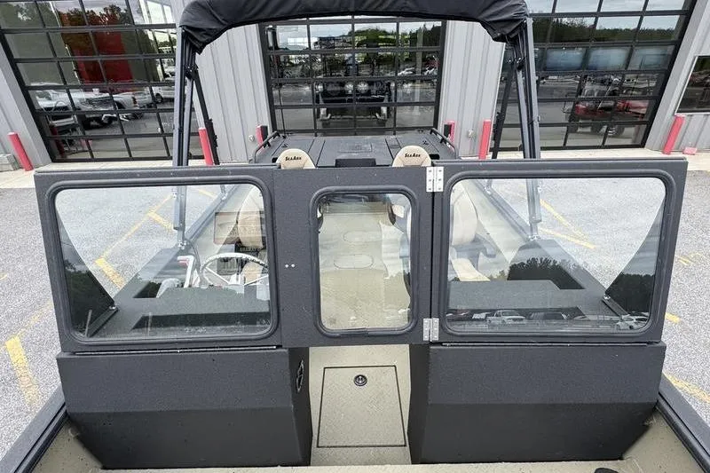 Slide: The Image of 2026 SeaArk Predator 300 AK boat with glass doors and seating, parked outside a building. - 13