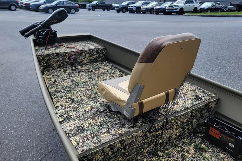 Slide: The Image of 2025 Tracker Grizzly 12 Jon boat with camouflage interior and tan seat, parked outdoors. - 6