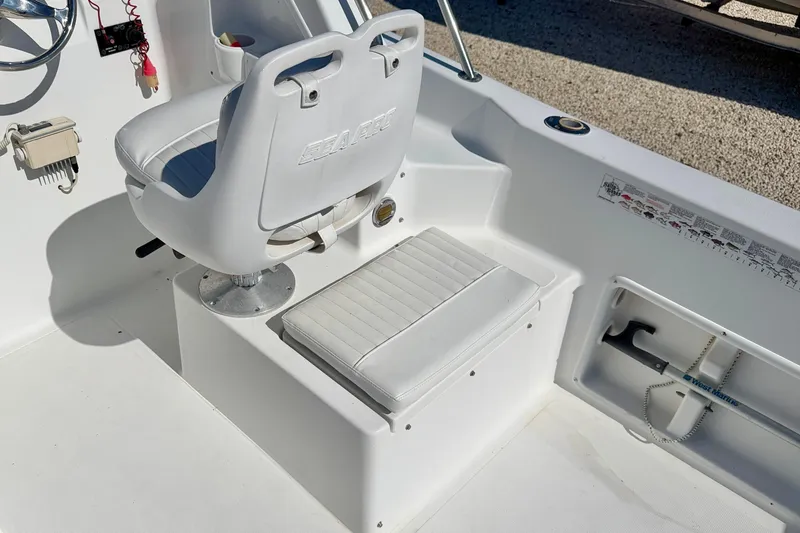Slide: The Image of 2005 Sea Pro 220 Walk Around boat interior with white seating and steering wheel. - 11