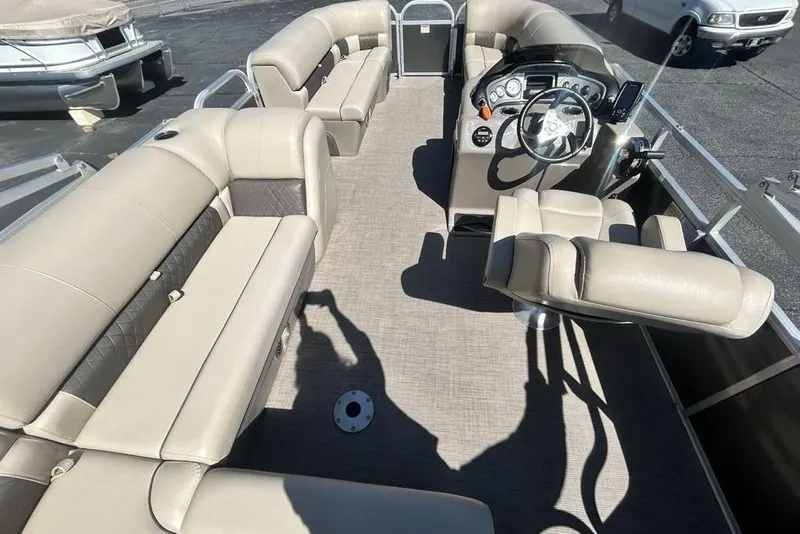 Slide: The Image of 2021 Sun Tracker Party Barge 20 DLX interior with beige seating and steering console. - 9