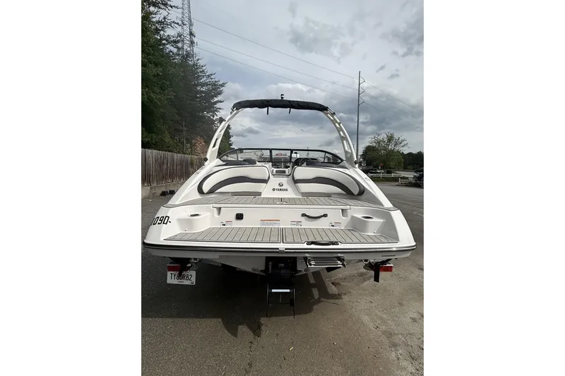 Slide: The Image of 2025 Yamaha Boats 195S, rear view, parked on a paved surface with trees in background. - 2